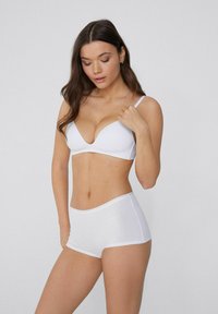 Conjunto de lencería blanca que incluye un sujetador con escote pronunciado y unas braguitas tipo hipster a juego. Hecho de una tela suave con costuras mínimas y líneas limpias.