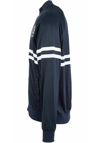 Veste bleu marine avec des rayures blanches, en tissu lisse. Comprend un col et des poignets côtelés, des poches latérales zippées et des détails brodés.