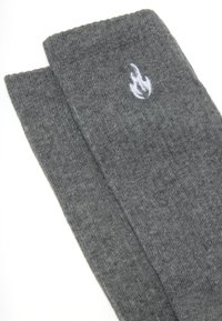 Calze grigie fino al ginocchio realizzate in un tessuto tricot texturizzato, con un piccolo logo a fiamma bianca su un lato.