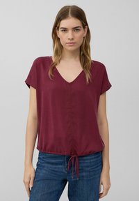 Bordeaux kortemouwblouse met een V-hals, voorzien van een geplooide onderkant met verstelbare koordjes en een soepele, lichte stof.
