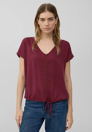 Blouse bordeaux à manches courtes avec décolleté en V, dotée d'un ourlet resserré avec cordons réglables et en tissu léger et doux.