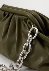 Torebka ze skóry w kolorze oliwkowej zieleni o marszczonym designie, z metalicznymi srebrnymi łańcuszkami i gładką teksturą.