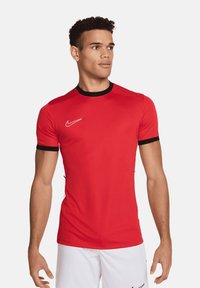 Maglietta sportiva rossa con rifiniture nere, maniche corte e logo Nike bianco sul petto. Realizzata in materiale leggero e liscio.