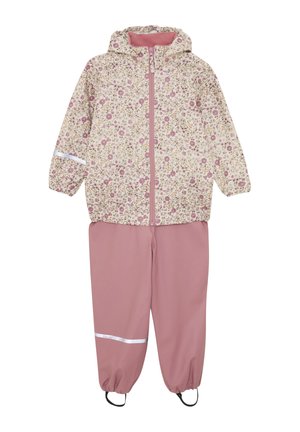 Impermeabile con stampa floreale color crema, abbinato a pantaloni impermeabili rosa con polsini elastici e dettagli riflettenti.