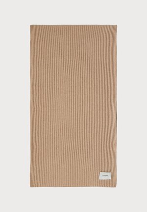 Écharpe en tricot beige avec des côtes verticales, dotée d'une petite étiquette blanche avec "IVY OAK" dans le coin inférieur droit. Texture douce, forme rectangulaire.