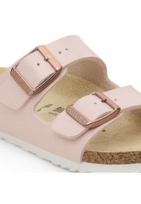 Sandalias de color rosa claro, con textura, que cuentan con dos correas ajustables con hebillas en color oro rosa, una plantilla de corcho y una suela de EVA blanca.