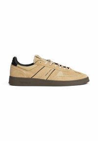 Beige Wildleder-Sneaker mit schwarzen Lederakzenten, featuring eine strukturierte Oberfläche, Schnürverschluss und einer braunen Gummisohle. Tommy Jeans-Branding inklusive.