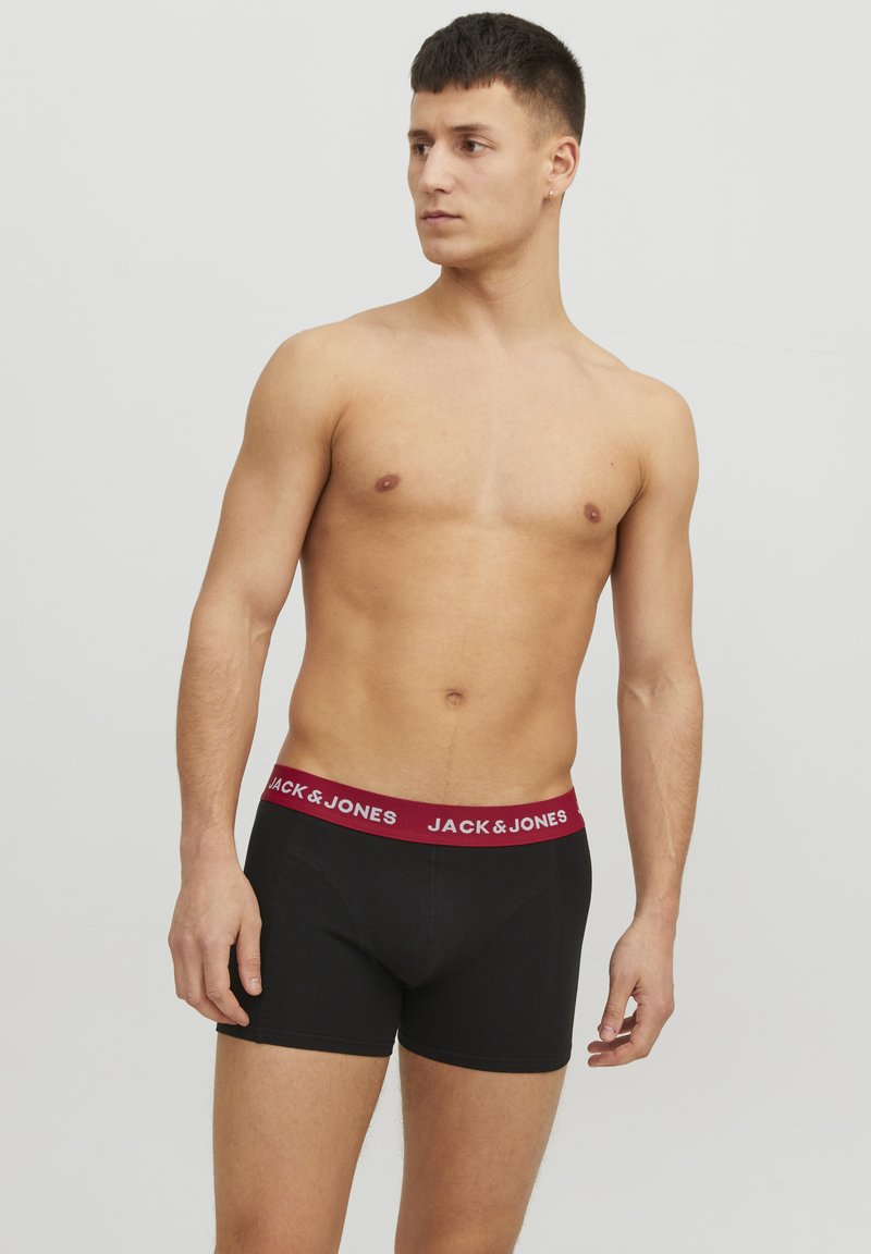 Schwarze Boxershorts mit einem burgunderrotfarbenen elastischen Bund, der mit weißen "JACK & JONES"-Schriftzug verziert ist. Glattes Material und taillierte Passform.