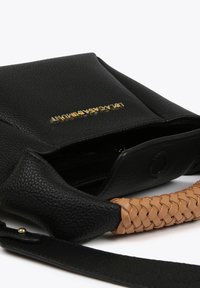 Black pebbled leather bag with a gold logo, featuring a braided tan handle and a magnetic snap closure. Interior space visible.