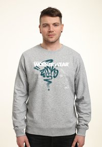 Šedá mikina s dlouhými rukávy a kulatým výstřihem, s grafickým potiskem označeným "WORKERWEAR" v bílé a tyrkysové barvě. Měkká textura.