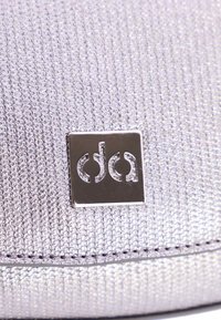 Bolso texturizado plateado con acabado metálico, que presenta una placa de logotipo brillante y acentos cosidos a lo largo del borde inferior.