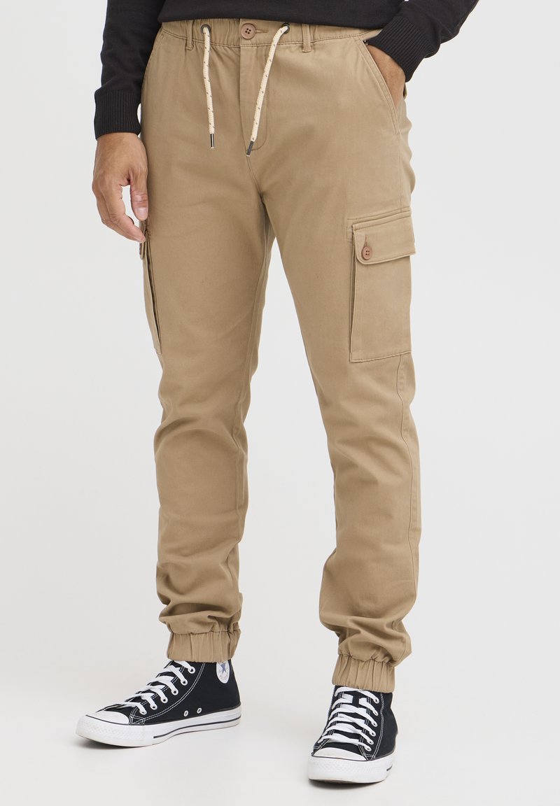 Kaki cargo bukser med elastiske manchetter, snørebånd i taljen og sidelommer. Stilet med sorte høje sneakers.
