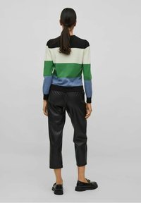 Raidallinen neulepaita vihreän, sinisen, mustan ja valkoisen sävyissä, yhdistetty mustiin nahkaisiin lyhytlahkeisiin housuihin. Pitkähihaisen mallin hihansuut ovat resoritettuja.