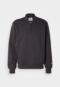 Sudadera negra de mezcla de algodón, con cuello de medio cremallera, dos bolsillos laterales, puños acanalados y un pequeño logo en el pecho.