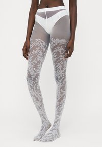 Gjennomsiktige grå strømpebukser med blomstermønster i lace, høy midje og glatt tekstur. Har åpen tå-design med subtil matt finish.