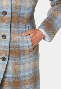 Wollmantel mit einem blau-braunen Karomuster, großen Knöpfen, einer Seitentasche und einer strukturierten Stoffoberfläche.
