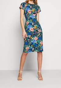 Bloemrijke jurk met korte mouwen, met een marineblauwe achtergrond en veelzijdige bloemen. Strak model, knielang, zachte stof en lichtgewicht.