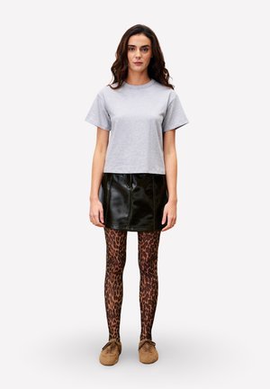 Grijze cropped t-shirt, zwarte neplederen mini-rok, legging met luipaardprint en bruine textuur instapschoenen.