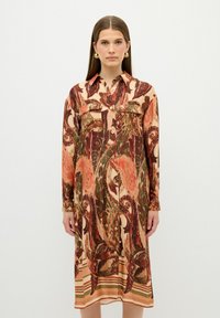 Langes, knopfbares Kleid mit einem Paisleymuster in erdigen Farben von Rot, Grün und Beige; aus glattem Stoff gefertigt; verfügt über einen Kragen und Taschen.