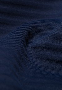Navy blue textured fabric with fine ribbing, creating undulating waves and soft sheen. Close-up detail highlights weave pattern and depth.