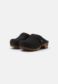Zoccoli in suede nero con punta arrotondata, suola in legno e dettagli cuciti. Due cinturini orizzontali sulla parte superiore aggiungono texture.