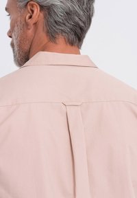 Lichtroze shirt met een klassieke kraag, een rugplooi detail en een gladde textuur, getoond van achter op een model met grijs haar.