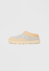 Grå og tan slip-on sko med overdel av filt, kontrasterende sømmer og en tykk såle i kremgummi. Rund form og minimalistisk design.