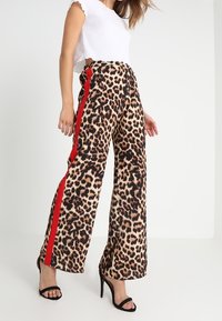 Leopard-Print-Stepphosen mit roten Seitenstreifen, aus weichem Stoff gefertigt; mit hoher Taille und entspannter Passform.