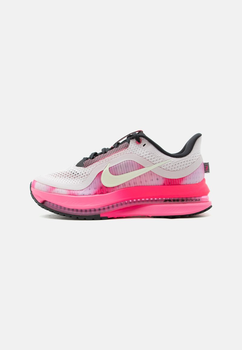 Λευκό και ροζ αθλητικό παπούτσι Nike με μαύρα κορδόνια, επάνω μέρος από δίχτυ, ορατή σόλα με αερόσακο και μεγάλο λευκό λογότυπο Swoosh στο πλάι.