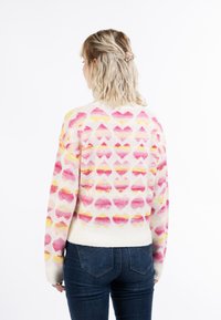 Strickpullover mit einem bunten Herzmuster in Pink, Gelb und Weiß auf einem cremfarbenen Hintergrund. Gerippte Bündchen und Saum.