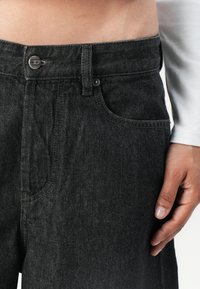 Sorte denim jeans med rett snitt. Funksjoner inkluderer knappelukking i midjen, beltehemper, frontlommer og synlige sømmer.