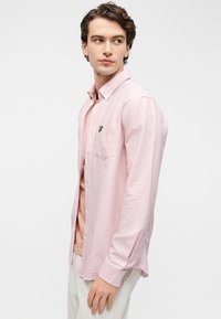 Ριγέ ροζ πουκάμισο με μακριά μανίκια και γιακά με κουμπιά, που διαθέτει τσέπη στο στήθος και λογότυπο της μάρκας. Μαλακό ύφασμα με άνετη εφαρμογή.