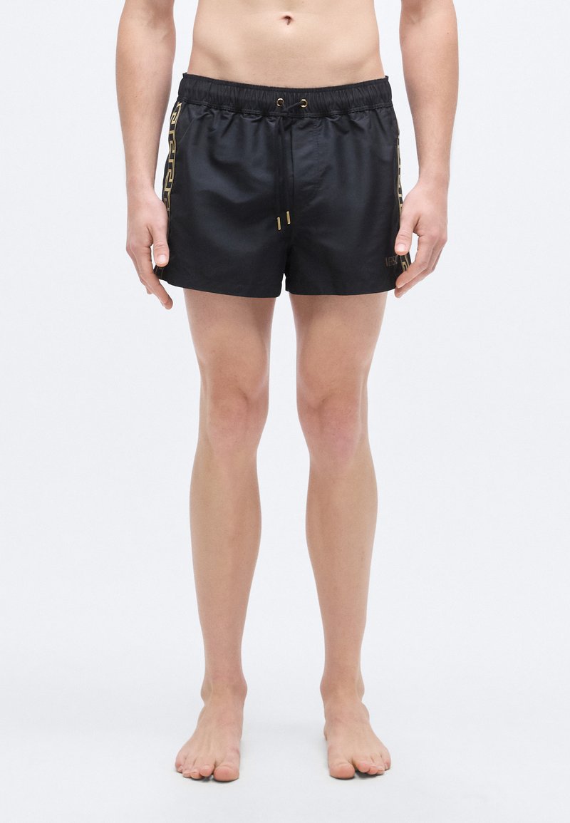 Μαύρο μαγιό βερμούδα με ελαστική μέση, χρυσές λεπτομέρειες και πλευρική φάσα με σχέδιο. Λείο ύφασμα με κλασική εφαρμογή.