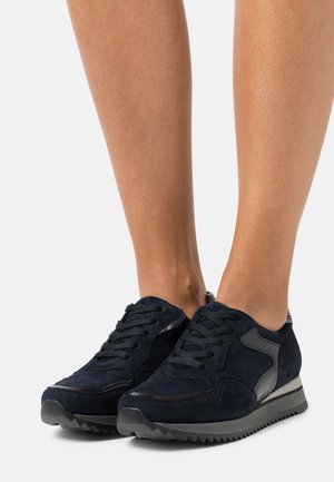 Navy blue suede sneakers with black textile accents, lace-up design, and a textured tread sole. Light cushioning visible near the ankle.