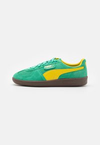 Baskets Puma Palermo en suede vert avec rayure jaune, semelle marron et doublure intérieure jaune, présentées en profil latéral sur fond blanc.