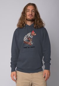 Marineblauwe hoodie van katoen, met een beer in een gestreept shirt en een rode hoed die op een fiets rijdt, met de tekst "Pour le France" eronder.