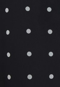 Granatowa tkanina o strukturalnej powierzchni z równomiernie rozmieszczonymi białymi kropkami, tworzącymi wyraźny wzór na materiale.