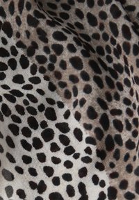 Tessuto a motivo con sfondo beige e macchie nere dense e irregolari, che presenta una texture liscia e forme di macchie variabili.