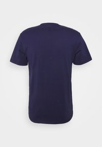 T-shirt en coton bleu marine avec des manches courtes, col rond et une texture lisse. La vue de dos montre un design simple, sans motifs ni accents.