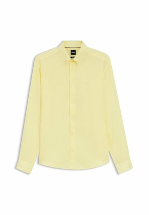 Camicia da uomo a maniche lunghe color giallo pallido, con colletto e bottoni, logo del marchio discreto sul petto, mostrata distesa su sfondo bianco.