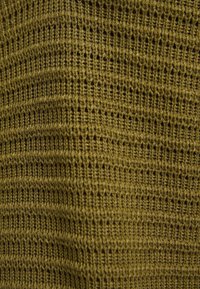 Gros plan sur un tissu en maille vert olive avec un motif texturé de points verticaux et horizontaux créant un effet côtelé.