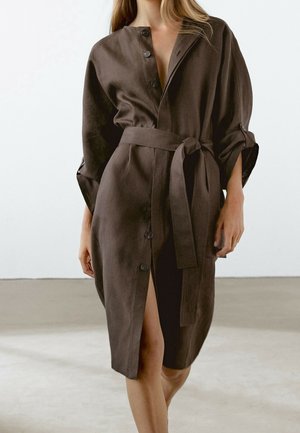 Bruine linnen jurk met een voorpand met knopen, brede mouwen en een strikceintuur. Heeft een gespleten ontwerp en een gladde textuur.