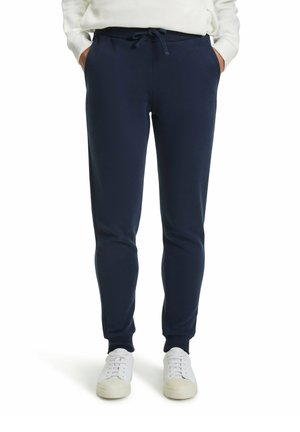 Marineblauwe sweatpants van zachte stof, met een trekkoord in de taille, taps toelopende beenen en zijzakken. Gecombineerd met witte sneakers.
