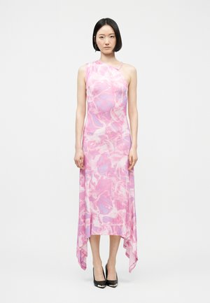 Ženska s črnimi ravnimi lasmi, oblečena v roza in vijolično eno-ramenno midi obleko z asimetričnim robom ter črnimi petami.