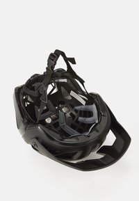 Svart sykkelhjelm med et interiørnett av polstring og ventilasjon. Har justerbare stropper og et solid, aerodynamisk design.
