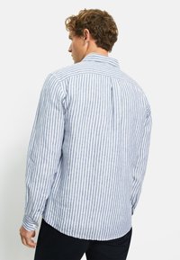 Camicia a maniche lunghe a righe in azzurro chiaro e bianco, realizzata in tessuto leggero. Caratterizzata da uno yoke posteriore, polsini con bottone e orlo arrotondato.
