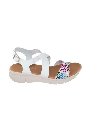 Sandalia blanca con correa ajustable en el tobillo, correa frontal multicolor, suela acolchada beige y cierre de hebilla sobre fondo blanco.