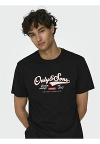 Camiseta de algodón negra con cuello redondo y mangas cortas, con texto impreso en rojo y blanco en la parte delantera, indicando la marca y el año.