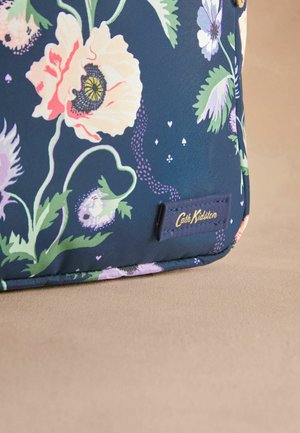 Tkanina za torbe s cvjetnim uzorkom na tamnoplavoj pozadini, s ružičastim i ljubičastim cvjetovima. Uključuje zlatnu oznaku Cath Kidston na plavoj tkanini.