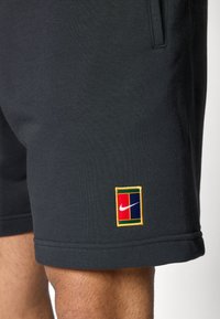 Fekete sportnadrág hímzett, színes Nike logós folttal a bal combján. Kellemes tapintású anyagú, és varrott szegéllyel rendelkezik.